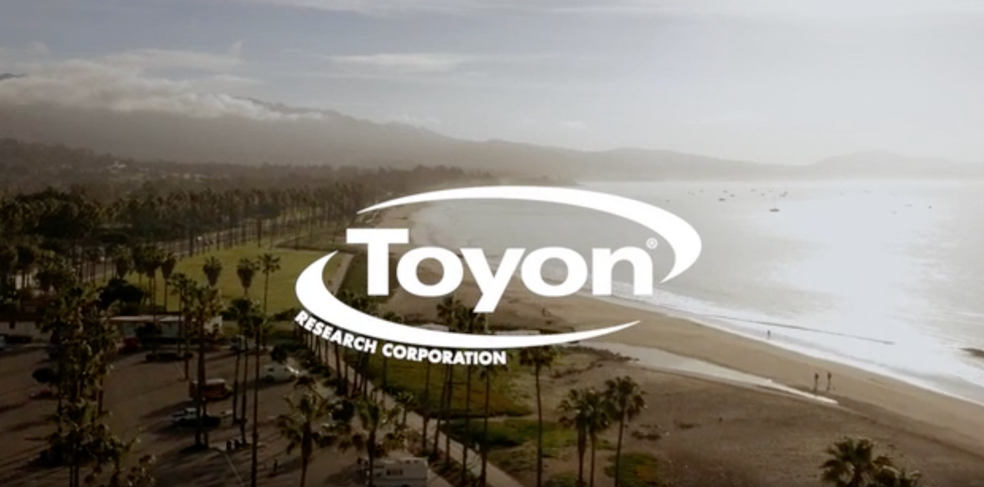 Toyon Research Corporation logo over a beach scene with ocean, trees, and mountains in the background.