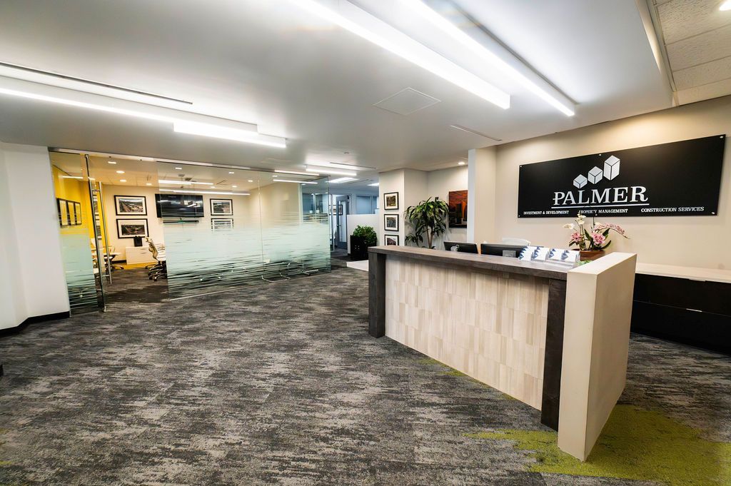 Office reception area with a wooden reception desk and logo sign.