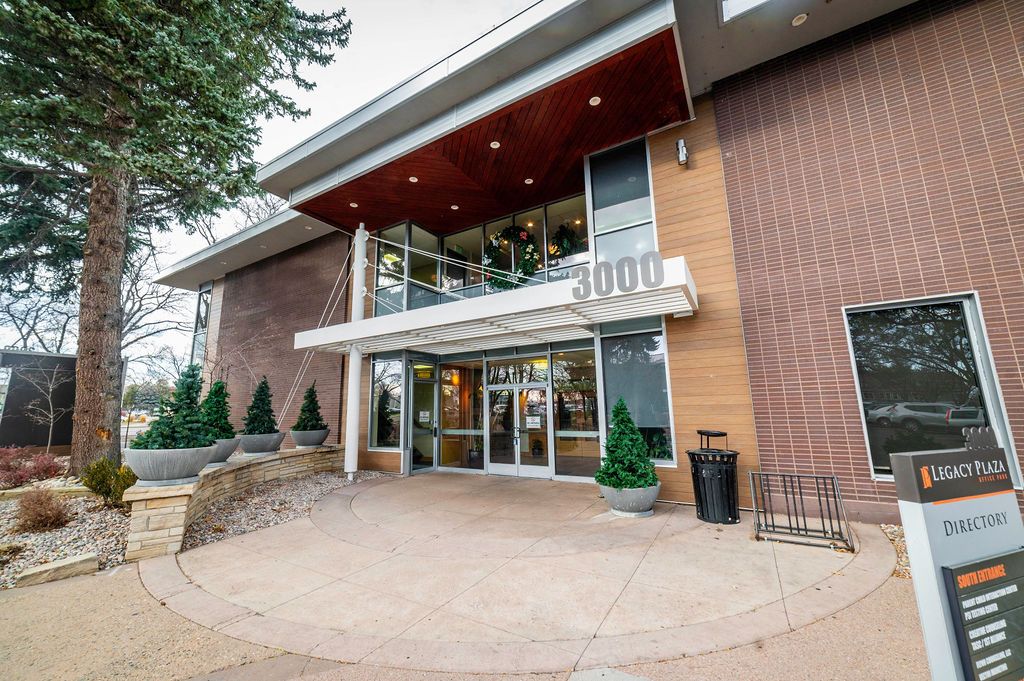 Entrance to a modern building with glass doors, a sign, and stone landscaping. The building exterior is brown.