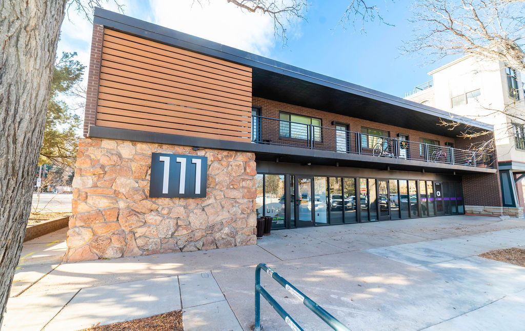 Exterior photo of a two story commercial building with exterior entrances and a stone corner