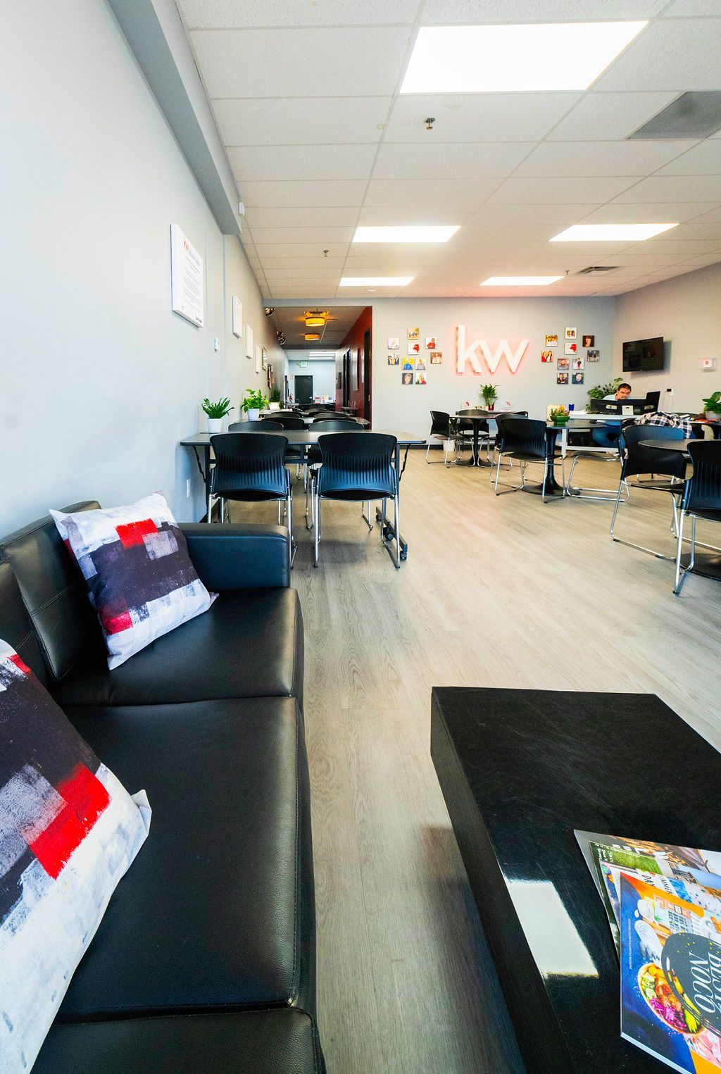 Modern office waiting area with black furniture, light wood floors, and a