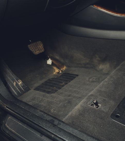 Interior of a car console with a gear shifter, climate control buttons, and circular air vents.