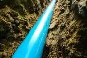 Bright blue pipe extending through a narrow rocky trench