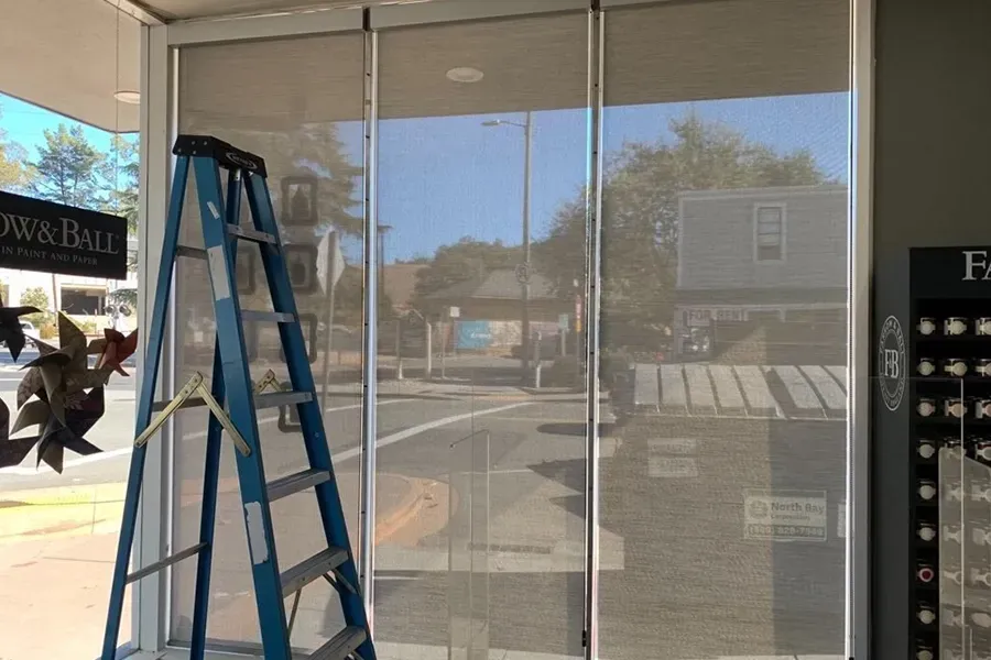 Blue ladder inside empty storefront with glass windows and reflections on the street