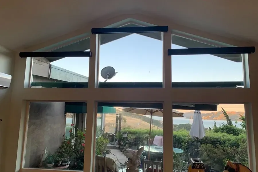 Window with open upper panes overlooking a patio and garden at sunset