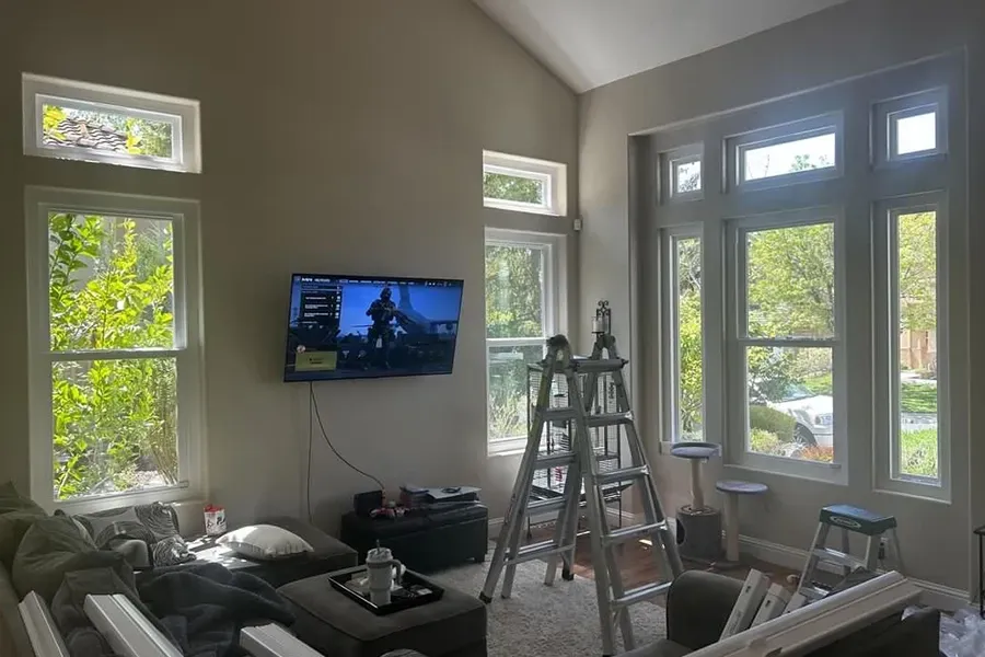 Bright living room with TV, ladder, and sunlight through many windows