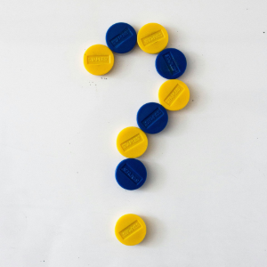 A question mark shape formed by alternating yellow and blue circular tokens on a white background.