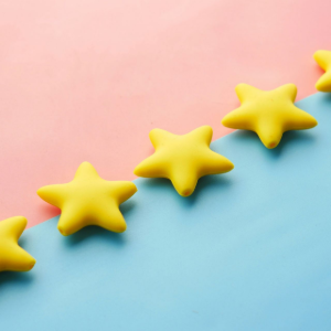 Five yellow star-shaped figures arranged in a diagonal line across a split pink and blue background.