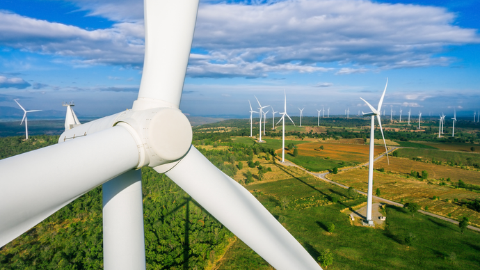 Wind turbines in a green field under a blue sky.