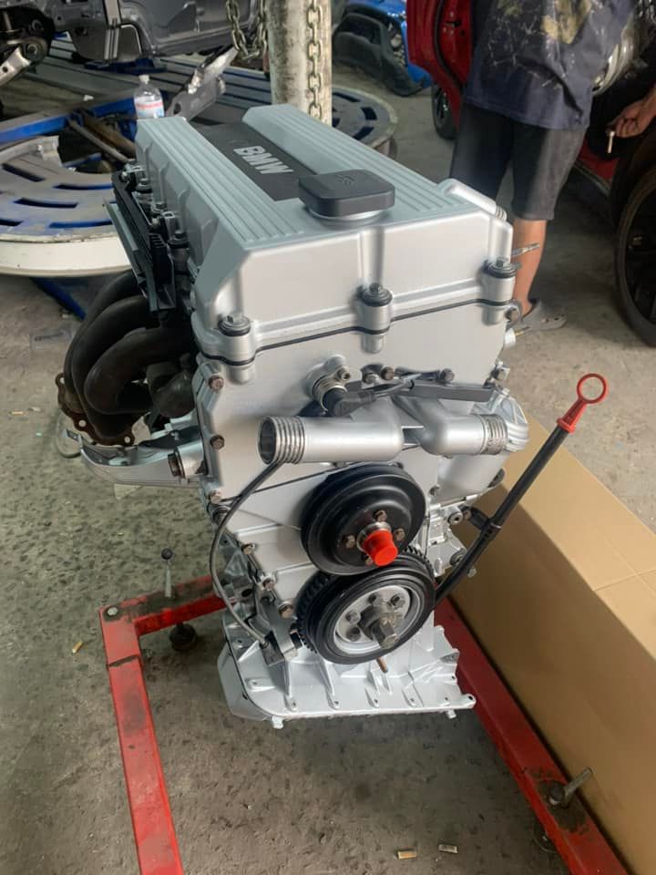 Silver car engine mounted on a red stand in a garage workshop
