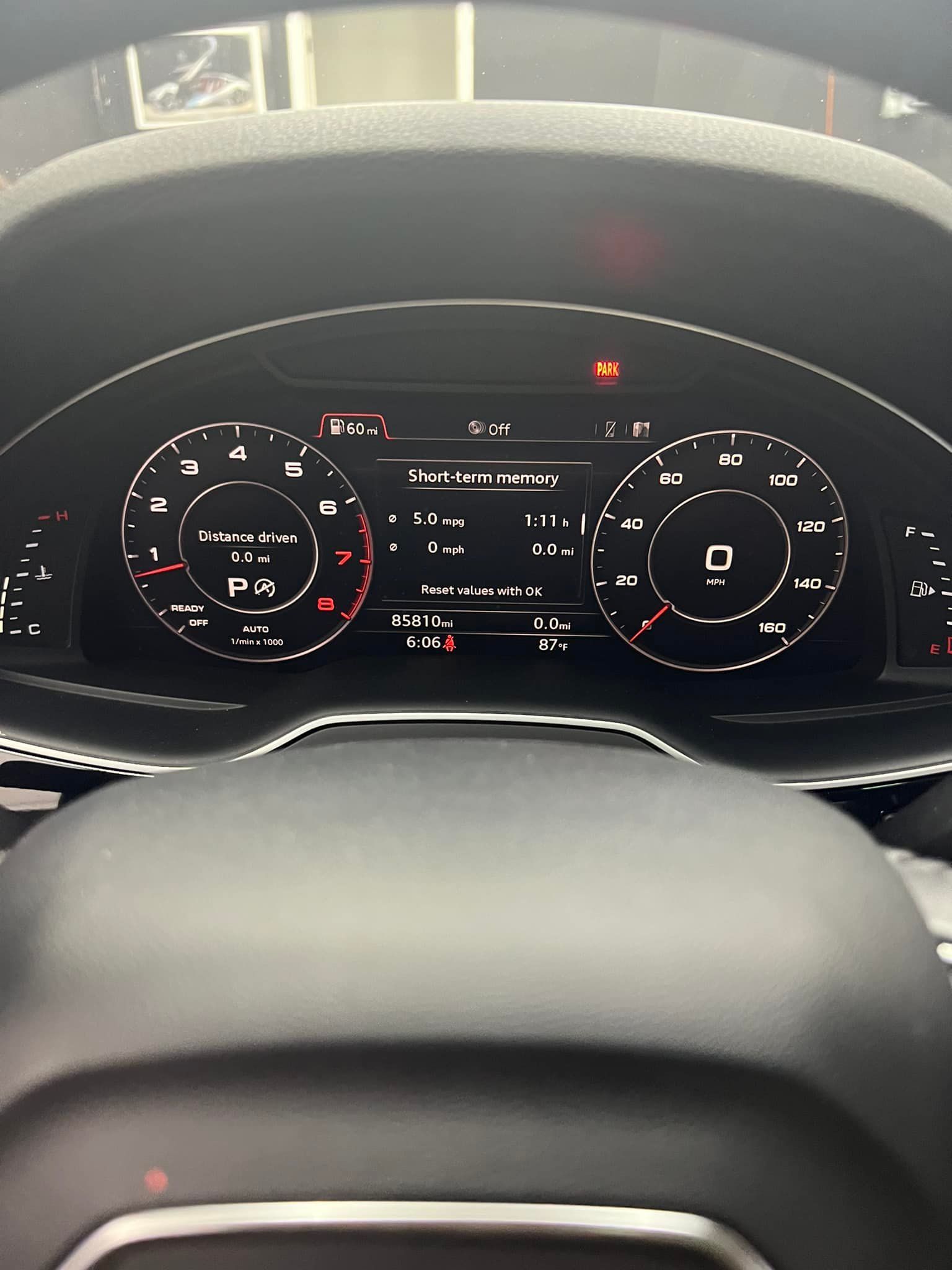 Car dashboard instrument cluster with digital speedometer and warning lights lit up.