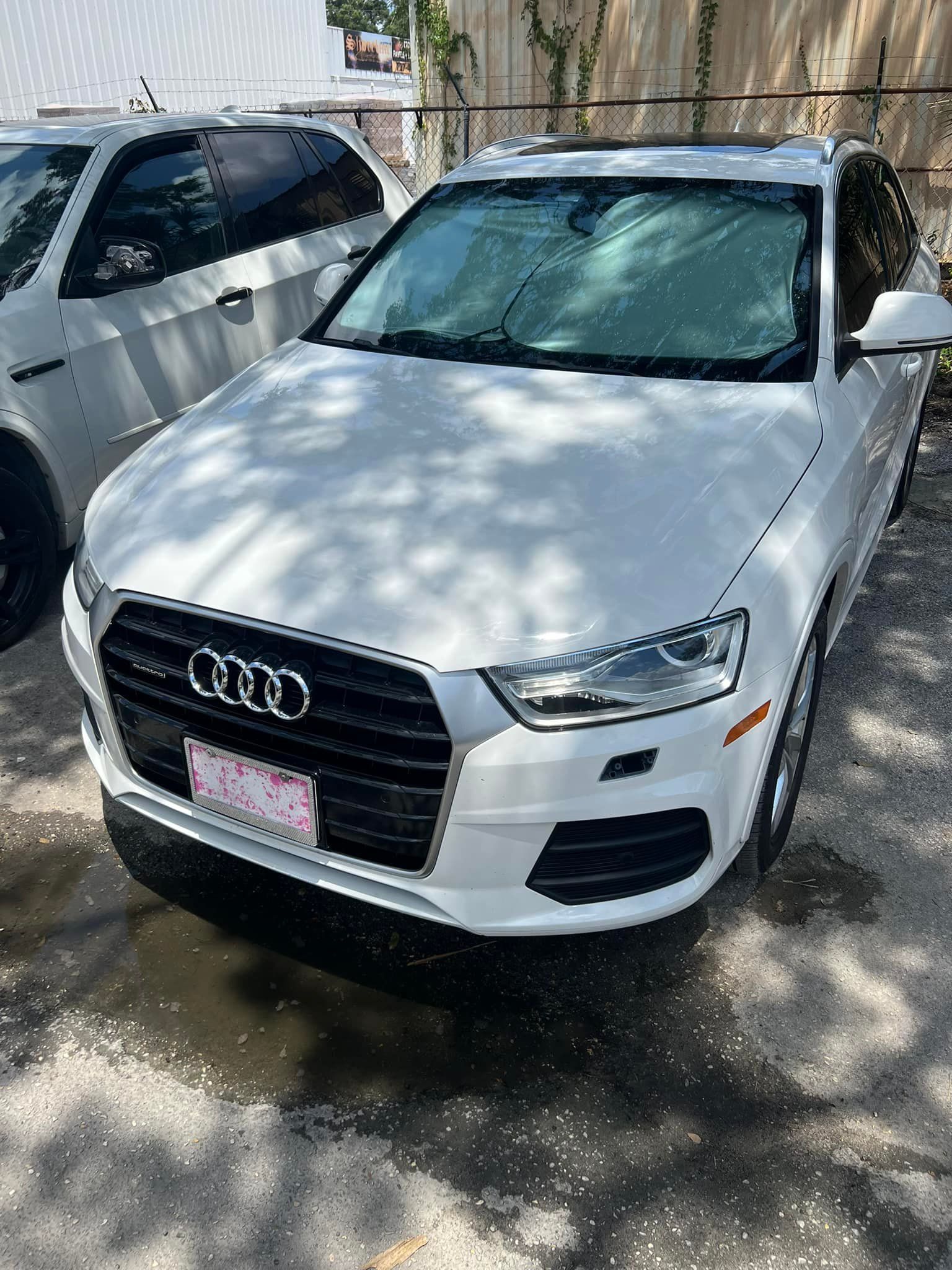 White Audi SUV parked outdoors in sunlight beside another vehicle