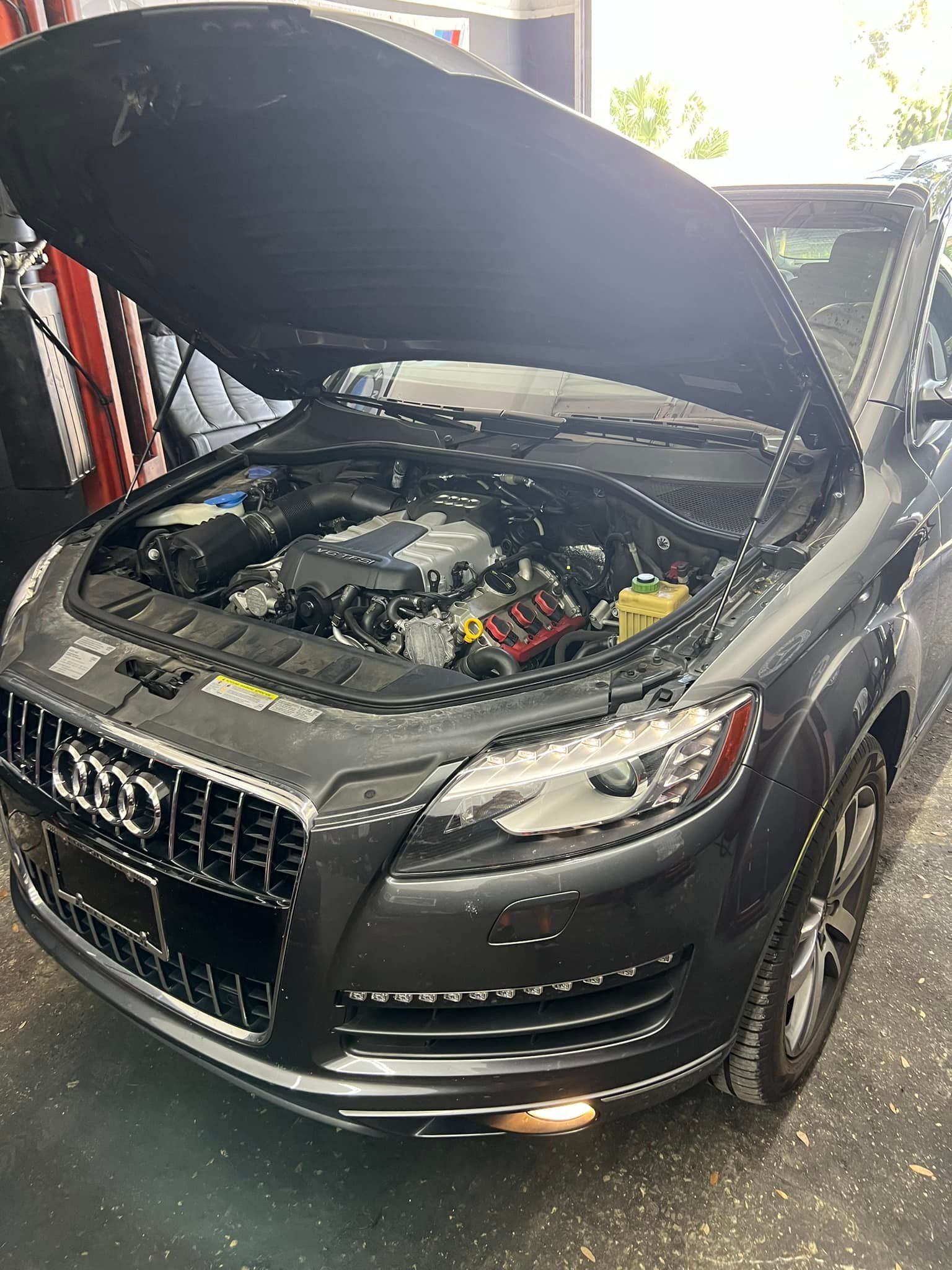 Black Audi SUV with hood open, showing the engine in a garage.