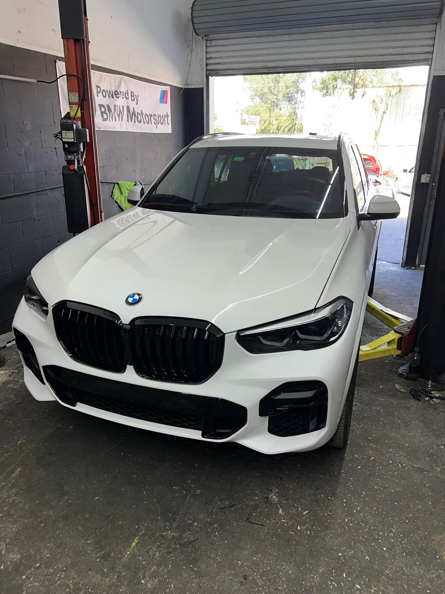 White BMW SUV parked in a garage bay, front view.