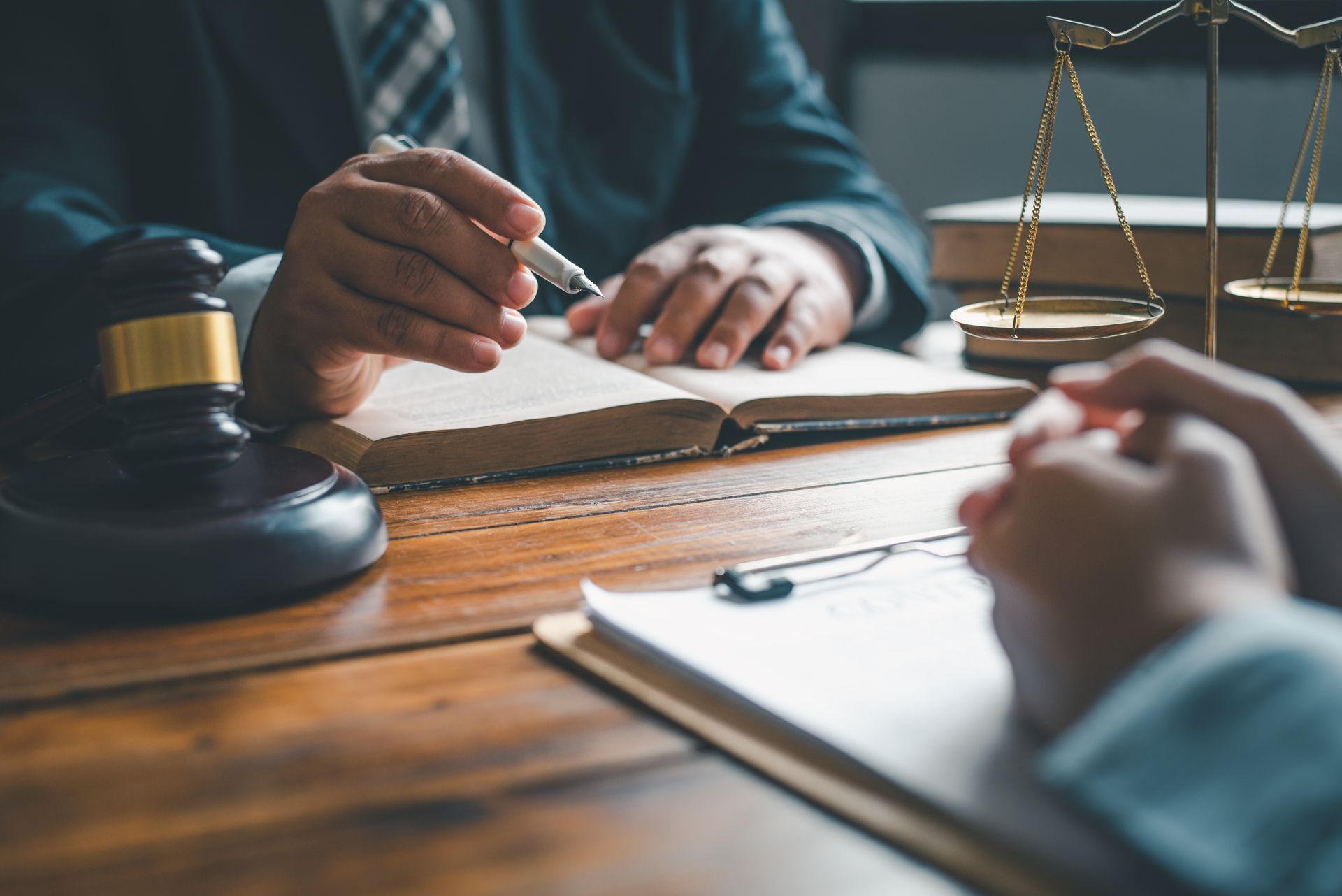 A judge is sitting at a table with a book and a scale of justice.