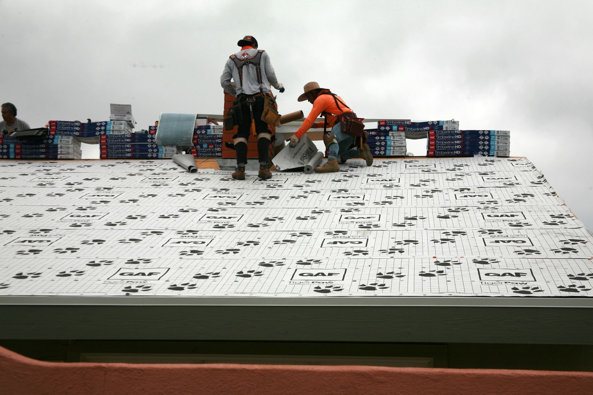 two men are working on a roof with a sheet that says gaf on it