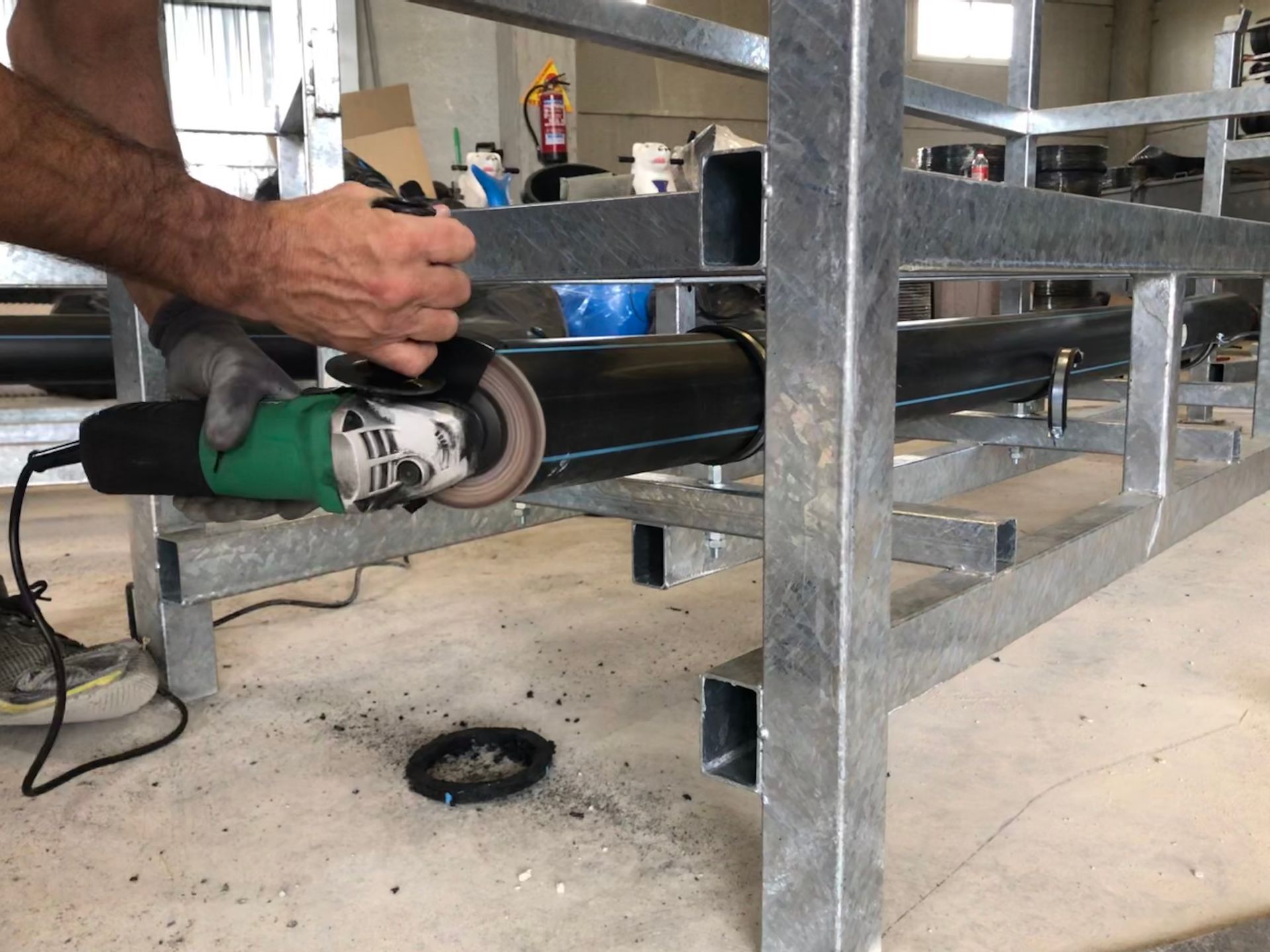 Un hombre está usando una amoladora en un tubo de metal.
