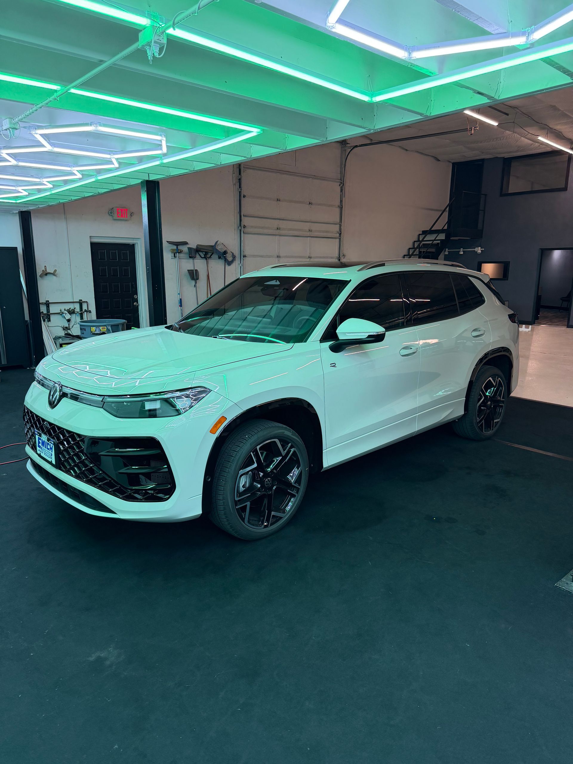 White SUV parked in a garage with green neon ceiling lights