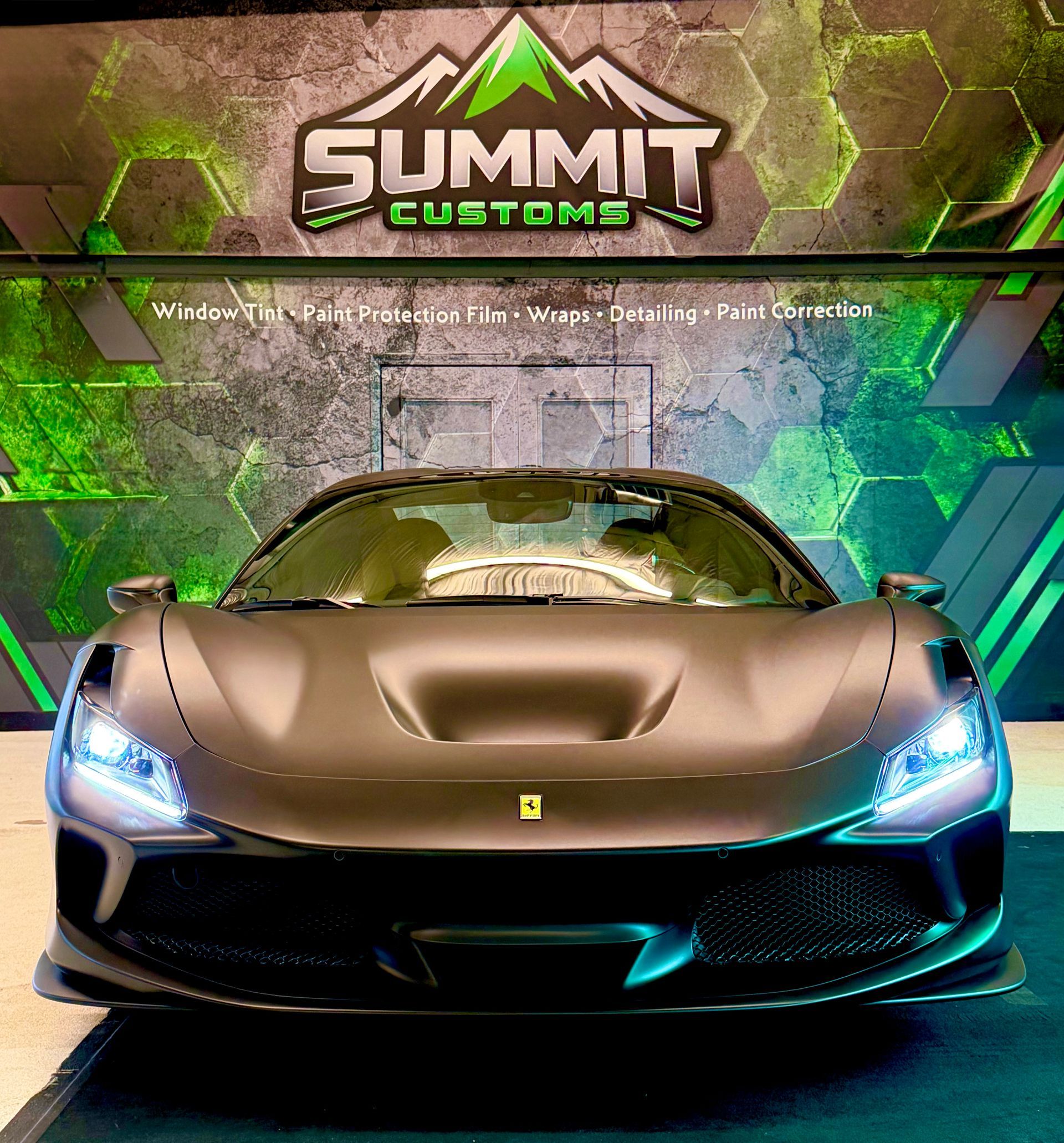 Sports car front view in a Summit Customs showroom, with neon blue headlights and a metallic finish