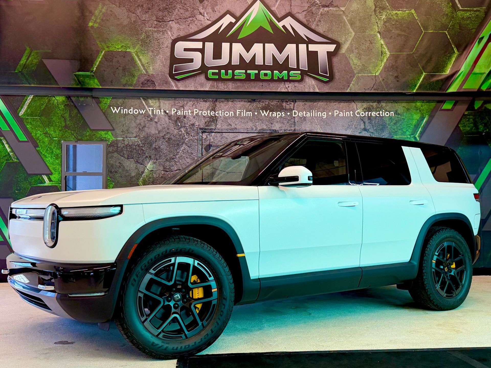Olive green off-road SUV with roof rack and black wheels parked on gravel outdoors.