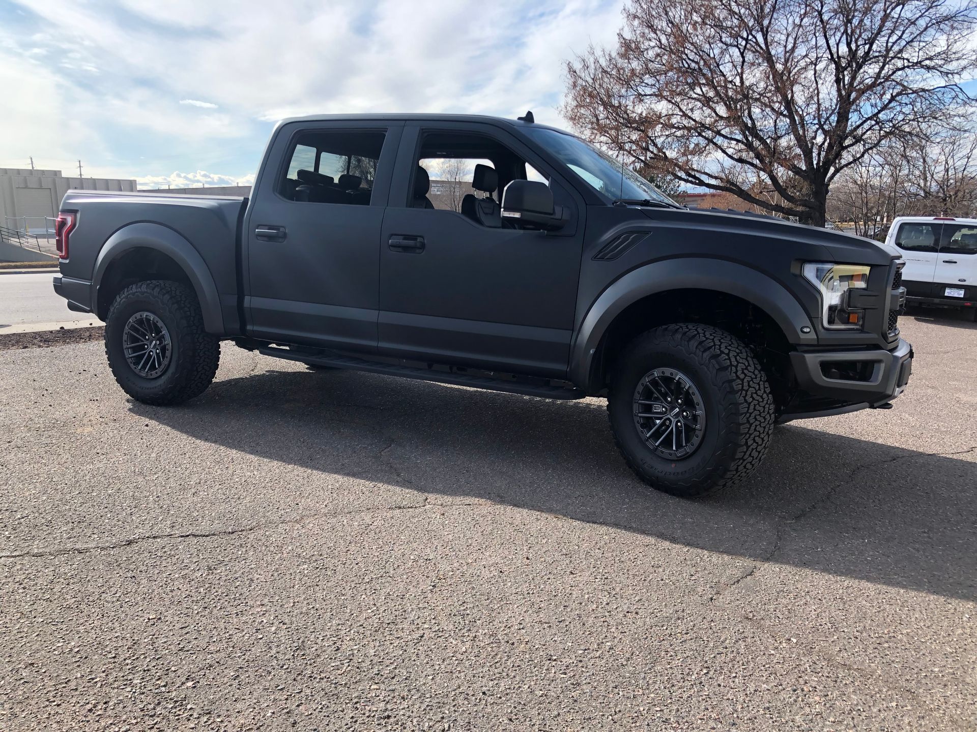 Black crew cab pickup truck parked on gravel in a sunny outdoor lot