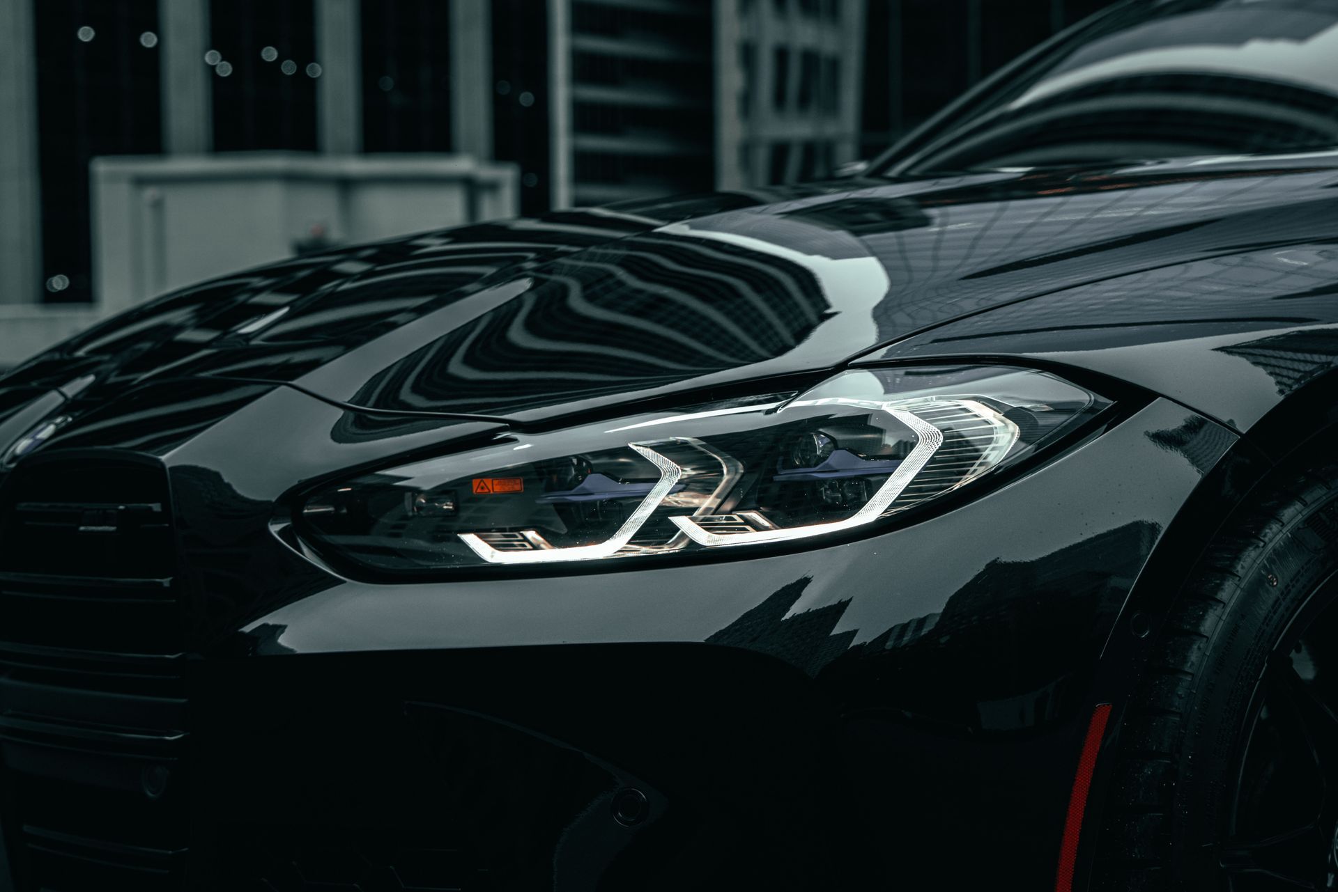 Close-up of a glossy black sports car headlight in a dim garage