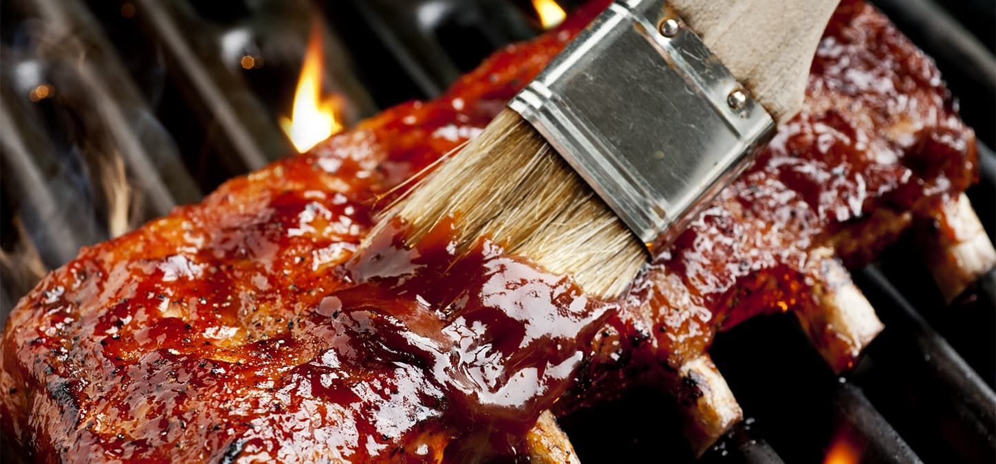 BBQ spare ribs being brushed with BBQ sauce