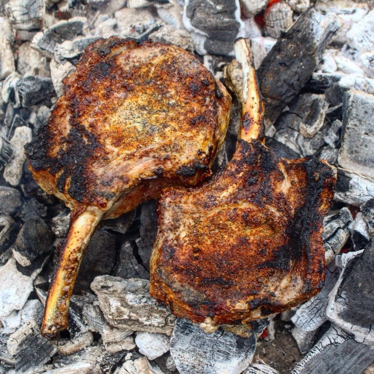 tomahawk pork chops cooking directly over hot coals