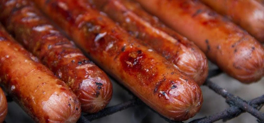 closeup of Hot dogs cooking on the grill
