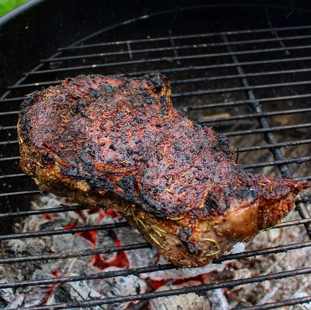 Bison ribeye steak cooking on the grill over live fire