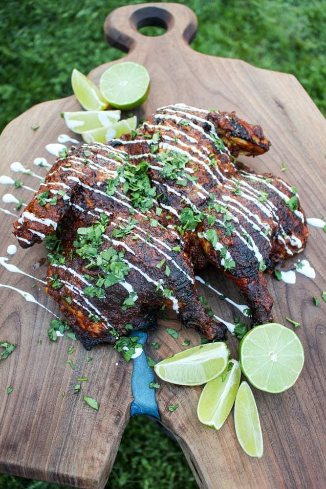 achiote lime pressed spatchcocked chicken garnished with lime wedges and sour cream