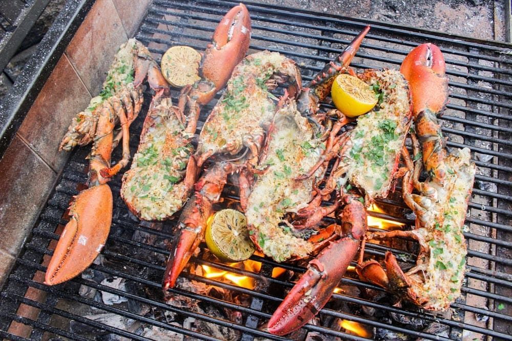 Lobster claws with seasoning and lemons cooking on the grill