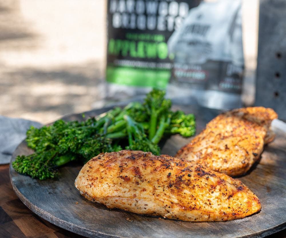 Grilled chicken breasts and broccolini on a wood plate; chicken breast grill; smoke chicken breast