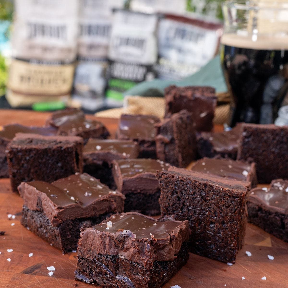 fudge brownies on a cutting board with glass of dark stout beer and Cowboy Charcoal in background