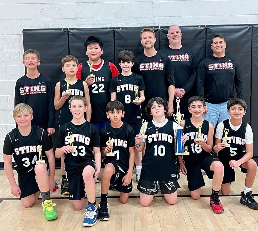 Youth basketball team and coaches posing indoors in black uniforms with gold lettering