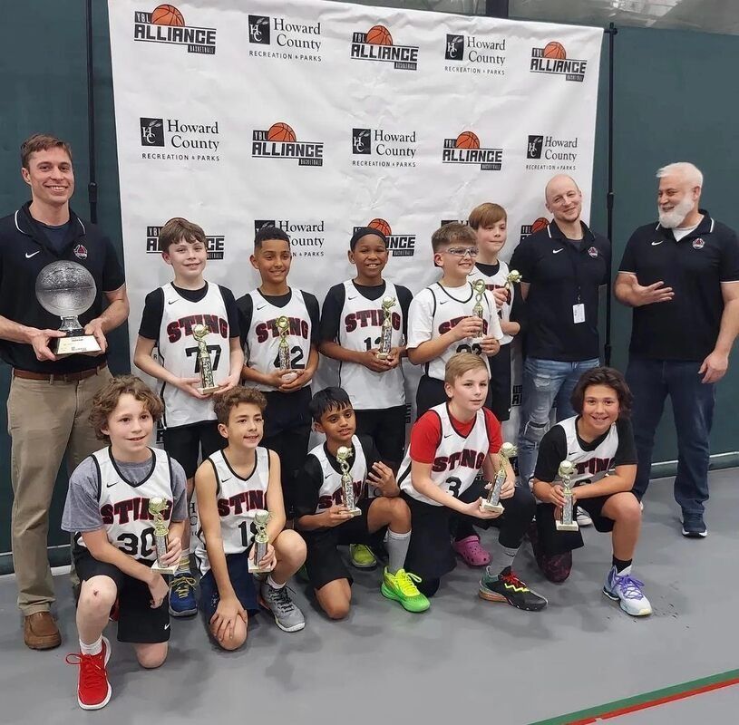 Youth basketball team posing with trophies at an indoor award ceremony