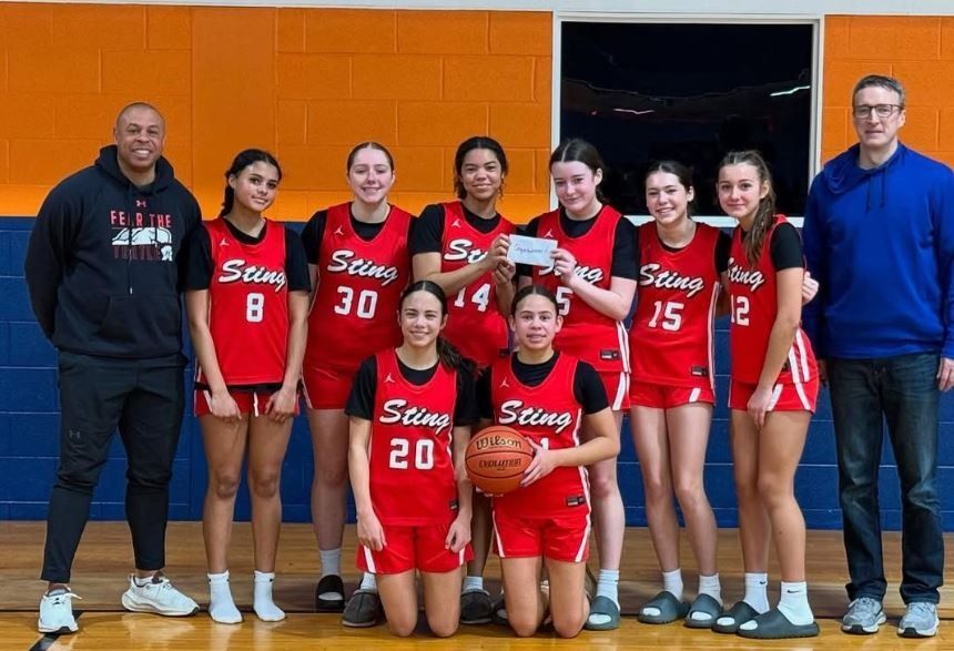 Seven players in red Steine basketball uniforms posing with two coaches in a gymnasium.
