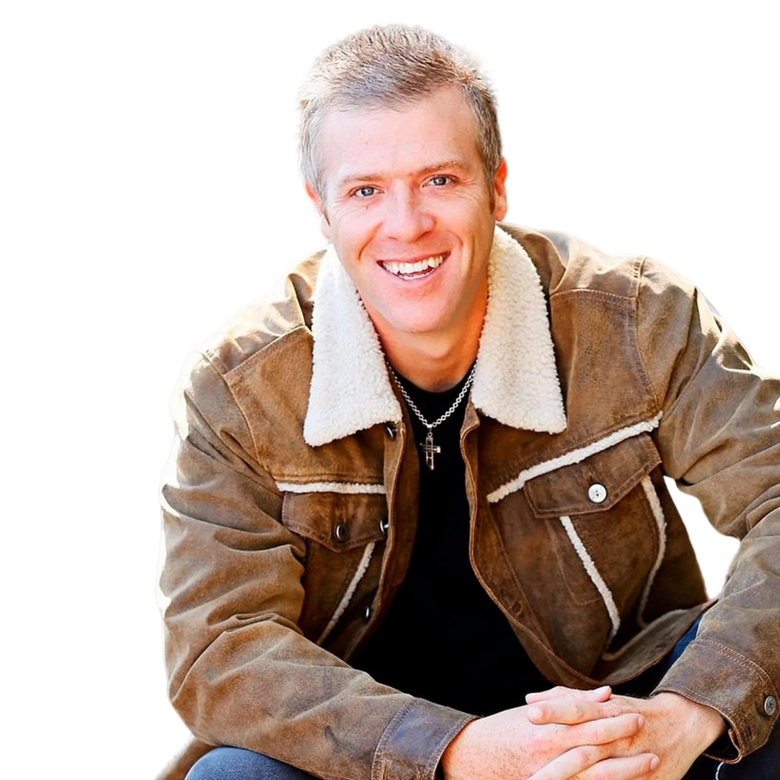 CONNOR STEINBROOK in a brown jacket is sitting with his hands folded.