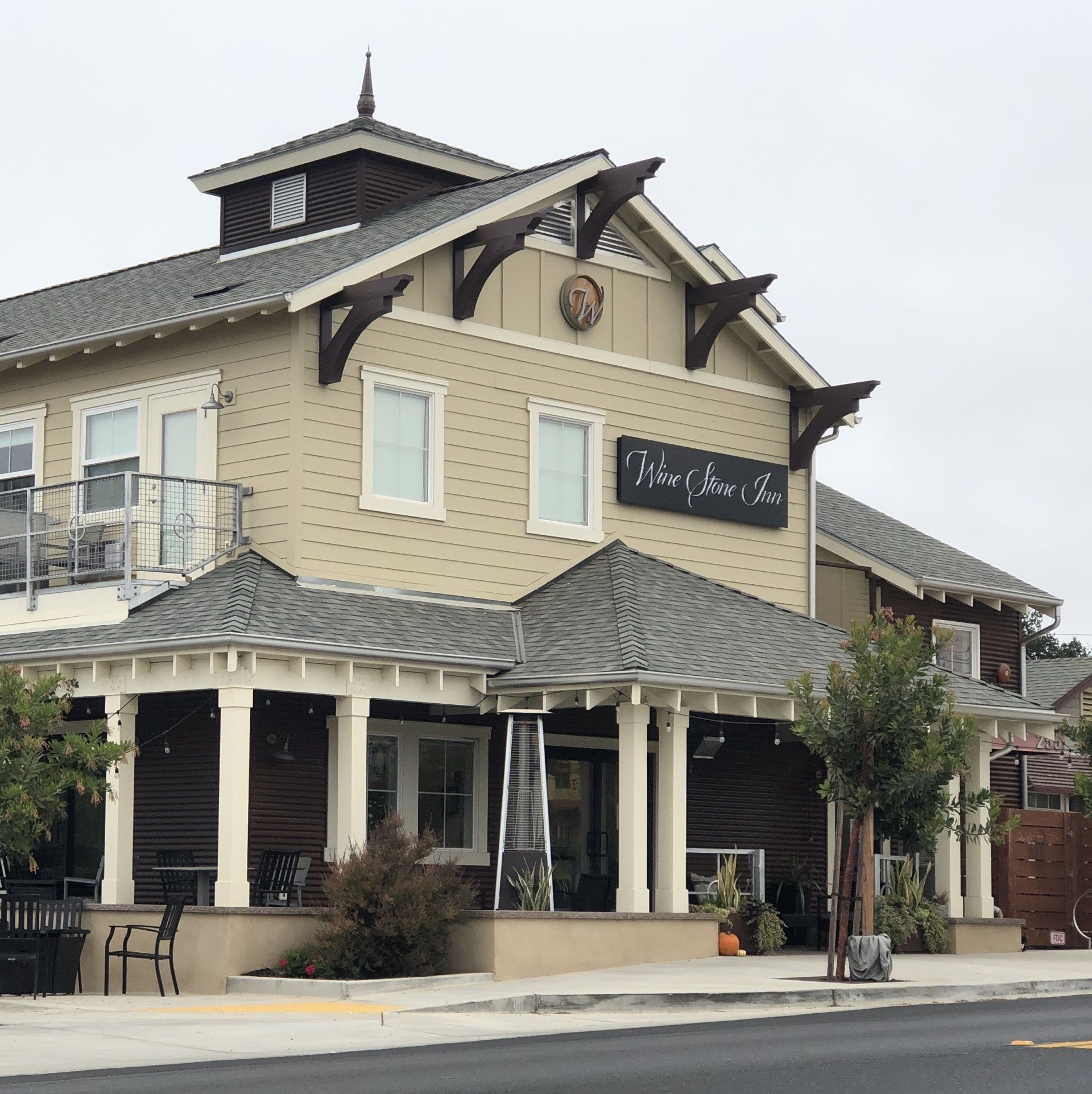 Two-story beige café with striped awnings and a porch on a street corner