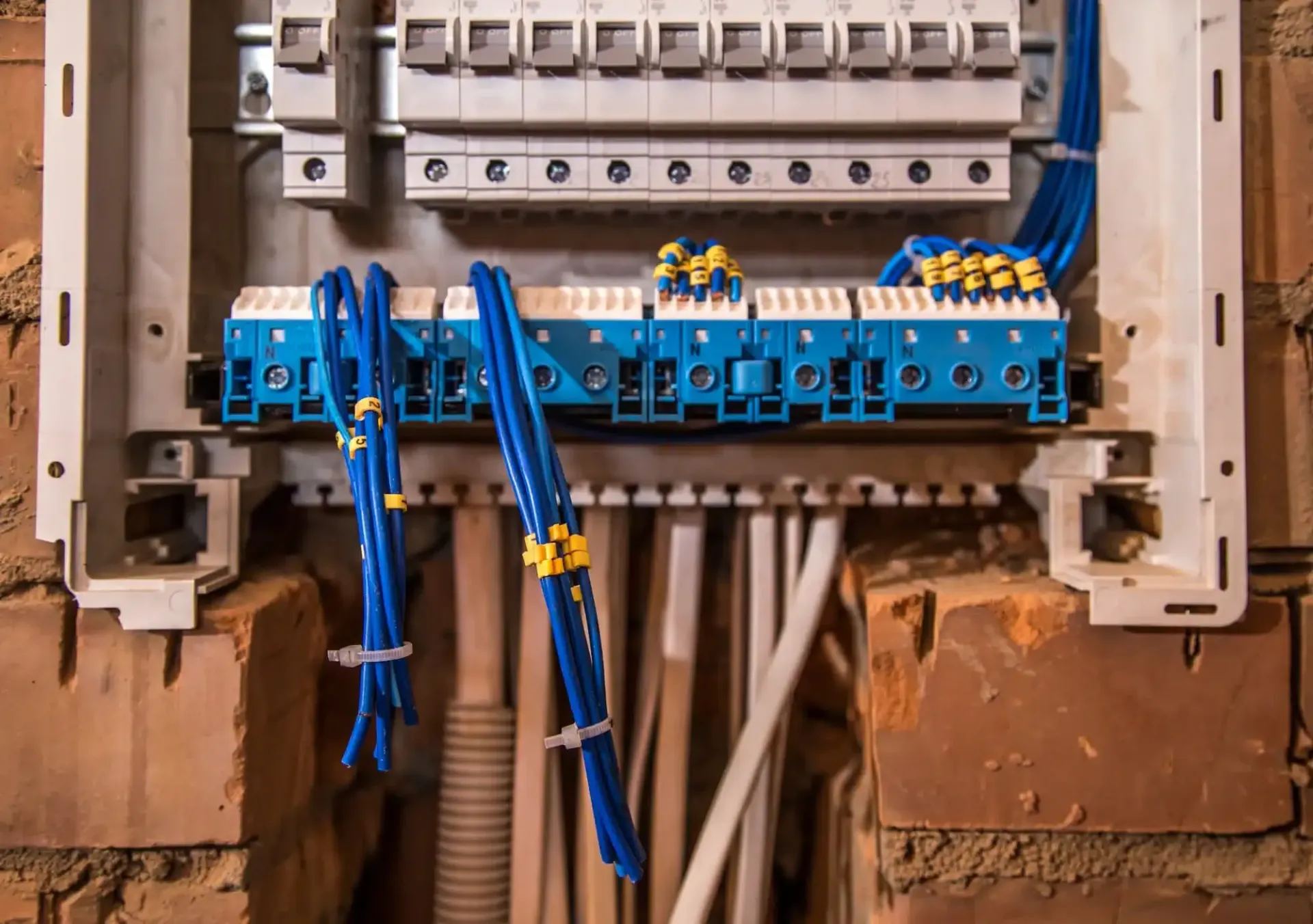 Blue electrical wiring and terminal blocks inside an open wall-mounted electrical panel.