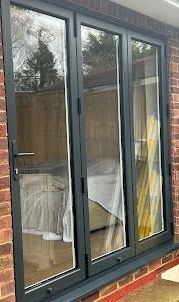 A large window with a lot of glass is on a brick wall.