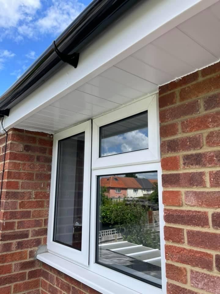 A white window is on the side of a brick building.