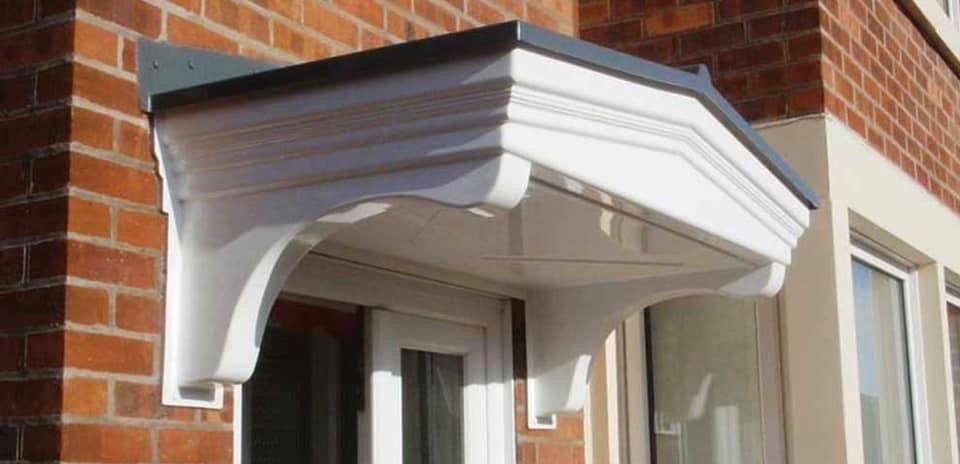 A white canopy is attached to the side of a brick building.