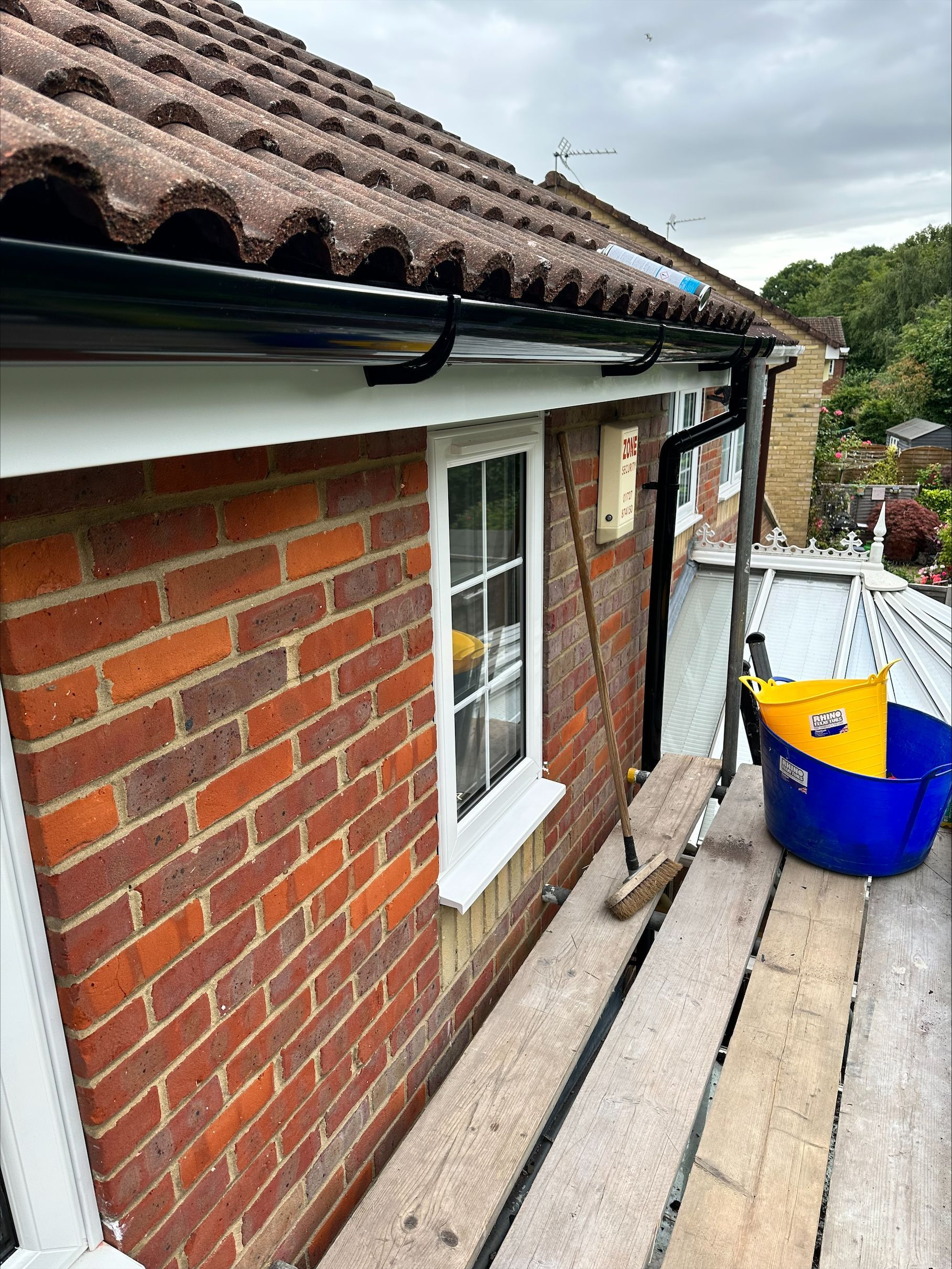 A brick house with a gutter on the side of it and a window.
