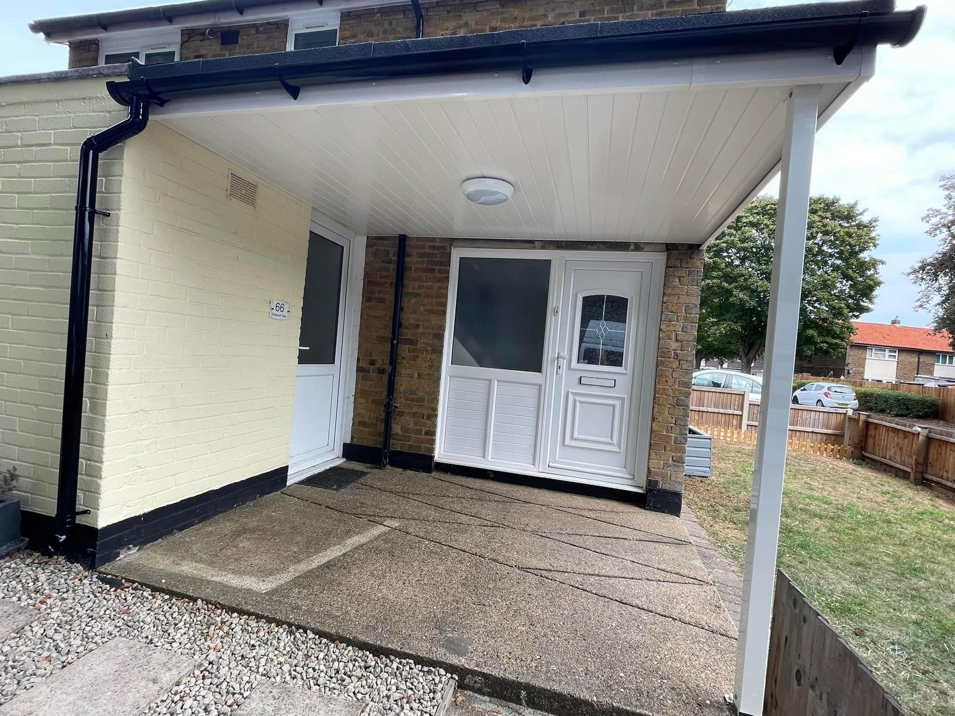 Covered porch with white ceiling, doors, and brick exterior.