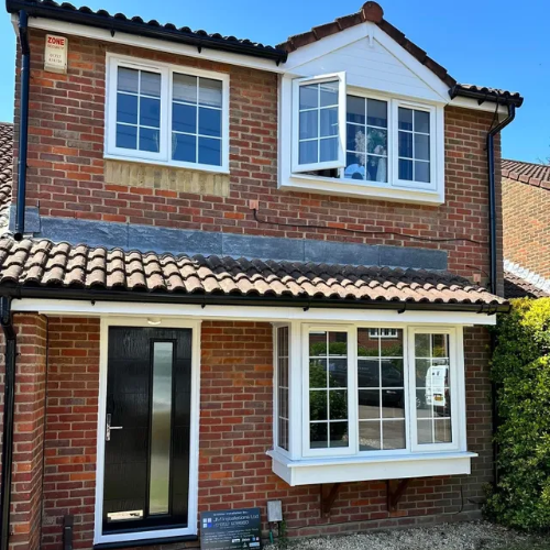Red brick house with white trim windows and black front door.