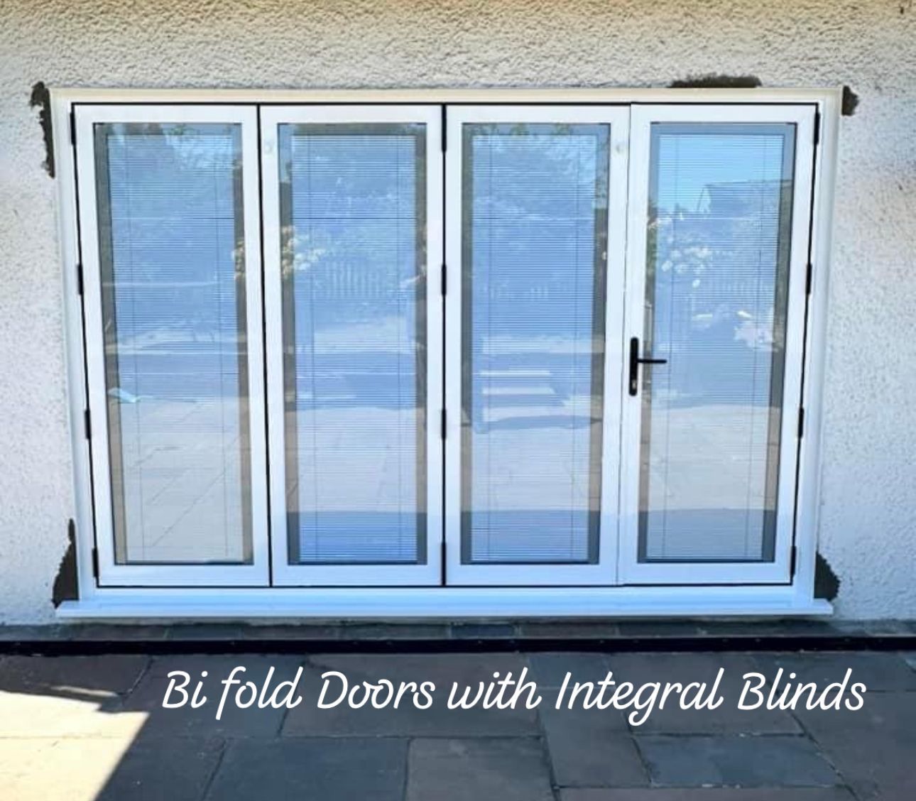 White bi-fold doors with integral blinds against a light-colored building. The doors are closed.