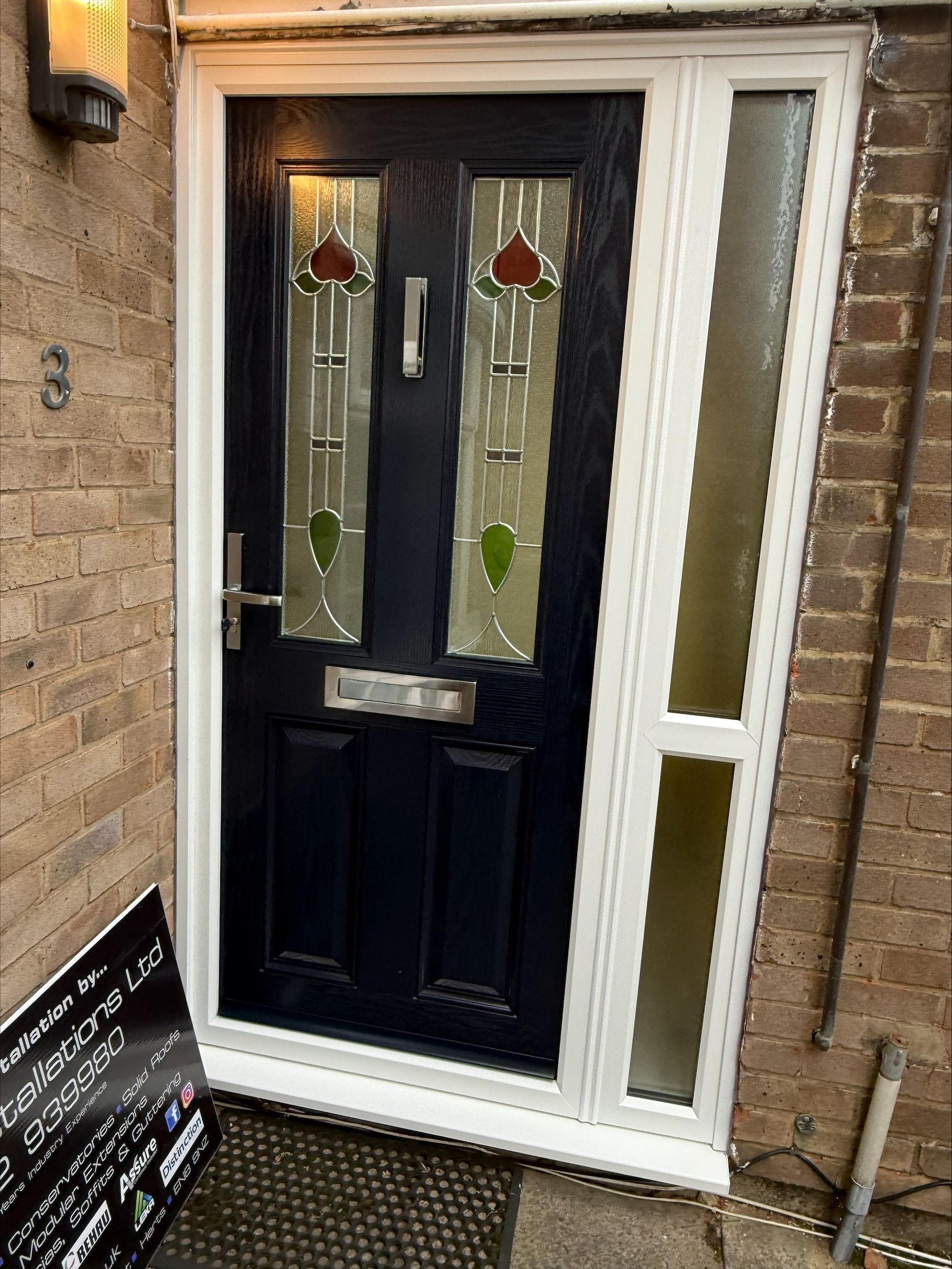Dark blue front door with decorative stained glass, white frame, and sidelight.