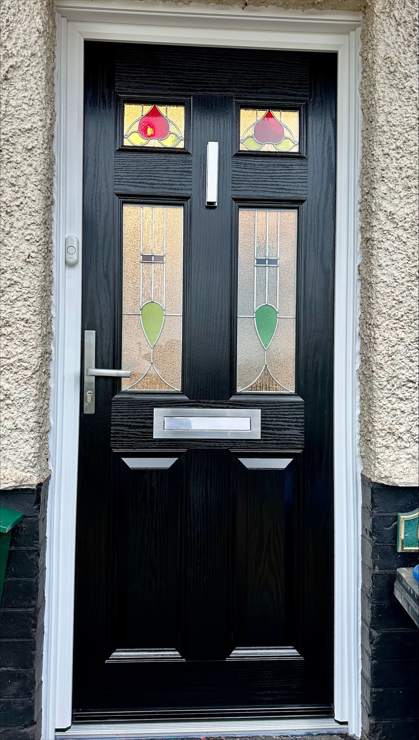 Black front door with decorative glass panels and white trim.