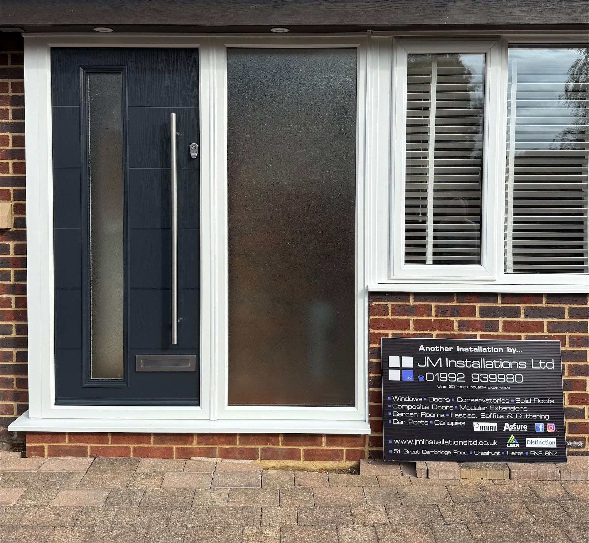 Front door with sidelight and window; blue door, textured glass, white frame, brick exterior.